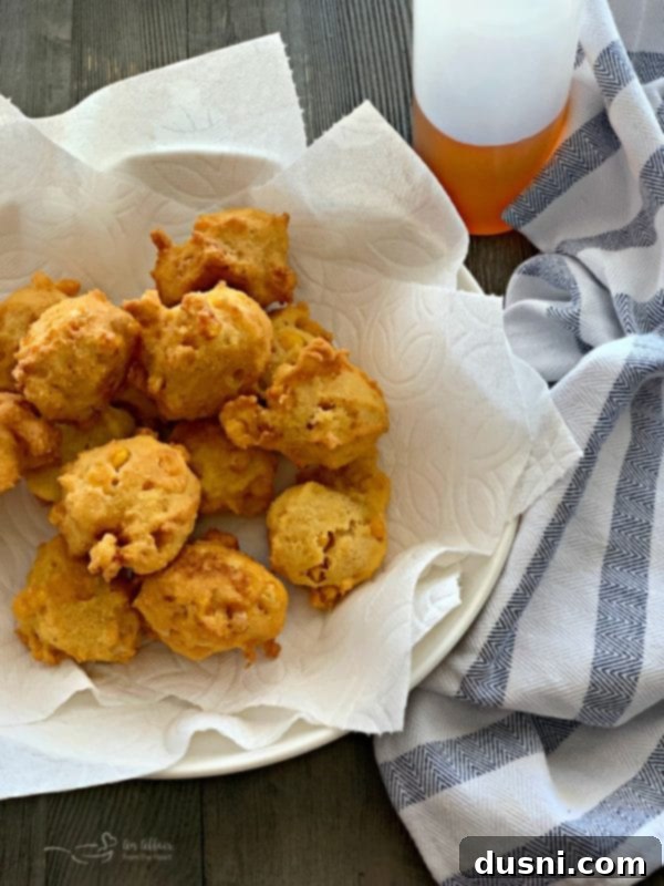 Freshly fried golden-brown corn fritters draining on paper towels.
