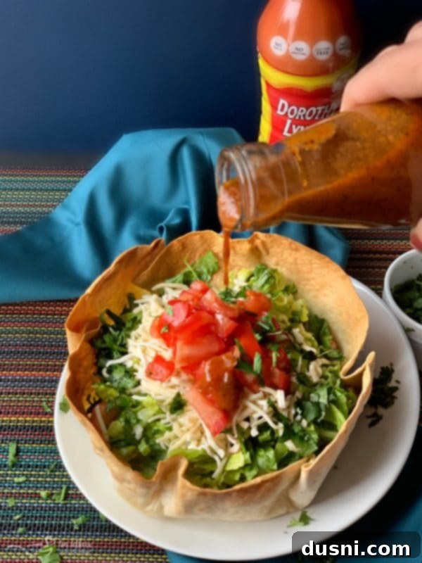Two fully assembled Dorothy's Taco Salads with Dorothy Lynch Taco Sauce, ready to be enjoyed