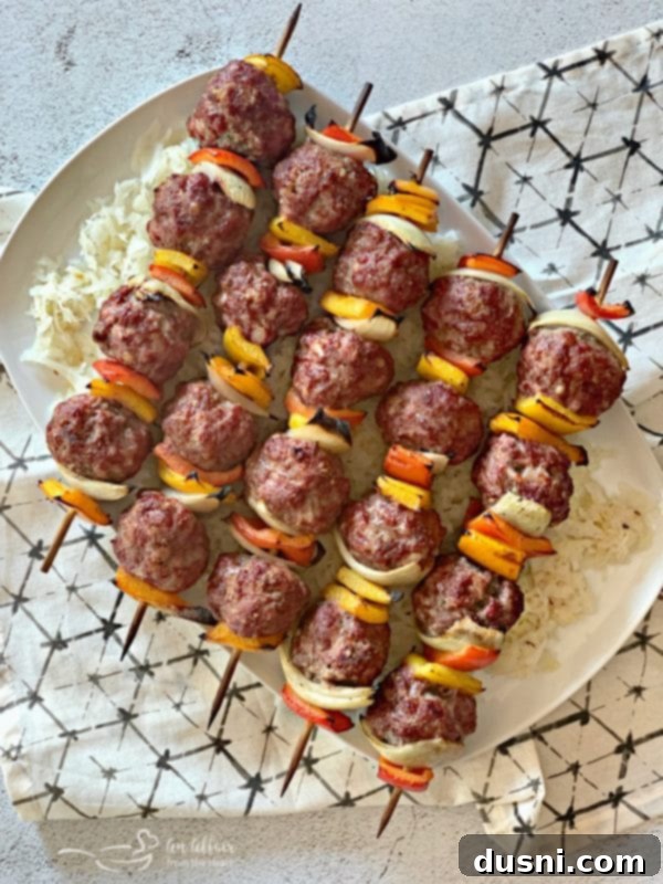 Sizzling Brat & Krautball Skewers 2 Grilled Bratwurst & Kraut Meatball Kabobs arranged on a platter with fresh kraut