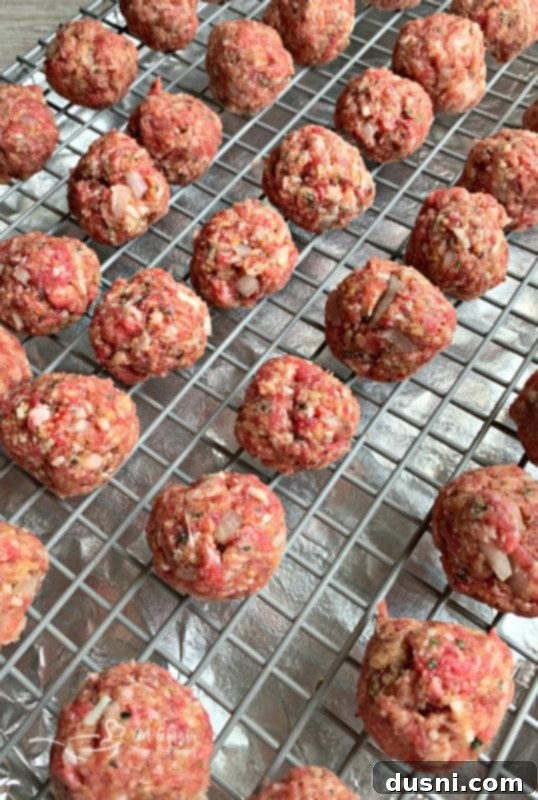 Meatballs placed on a wire rack over a foil-lined baking sheet