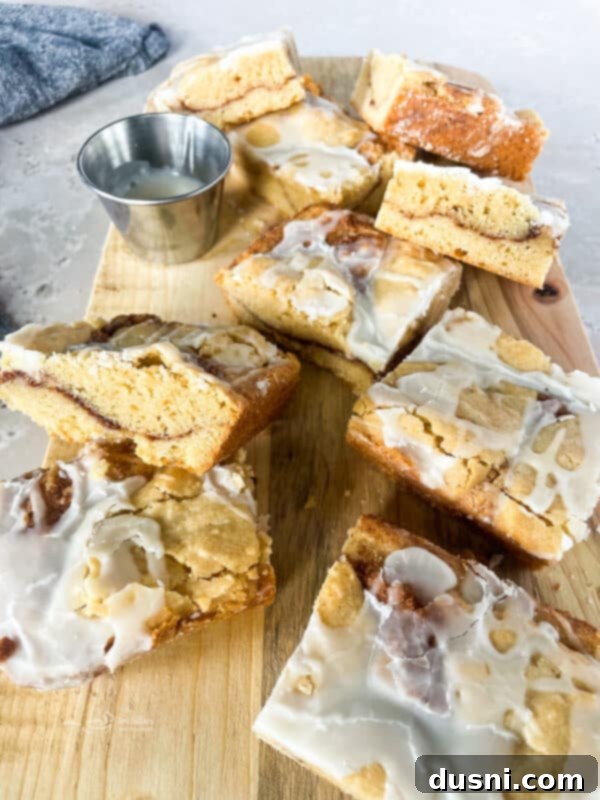 Glazed Snickerdoodle Bars 16 A plate of Iced Snickerdoodle Bars, with one bar bitten into, revealing the soft interior.