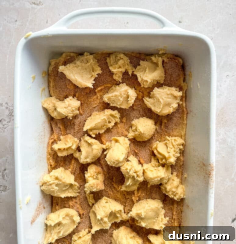 Glazed Snickerdoodle Bars 10 First layer of snickerdoodle cookie dough spread in a baking pan, topped with cinnamon sugar.