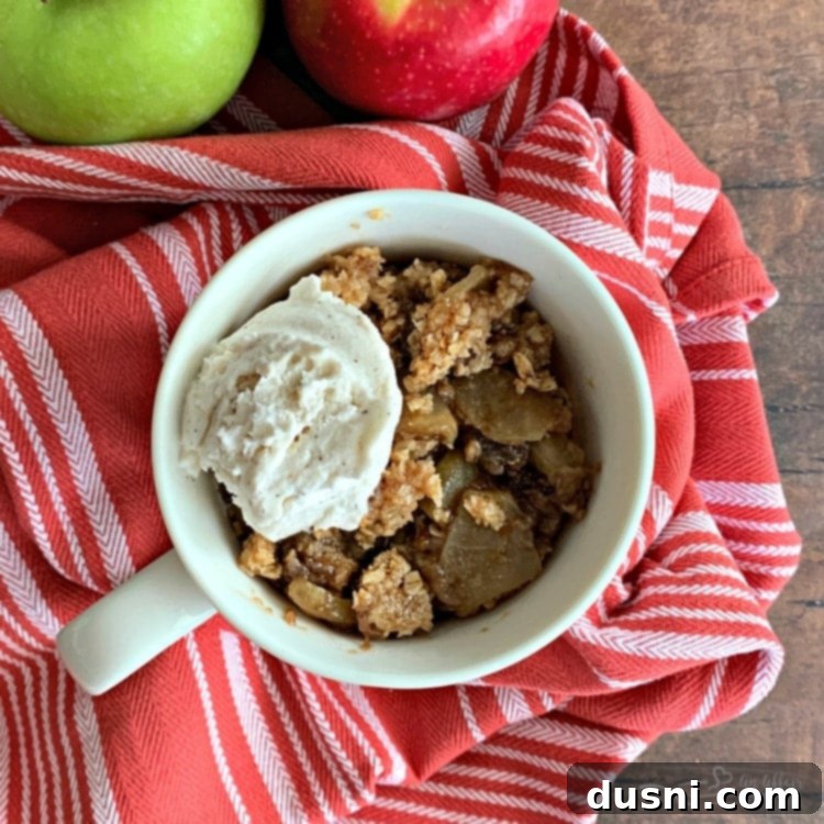 Warm Apple Crisp in a Mug topped with a generous scoop of melting vanilla ice cream