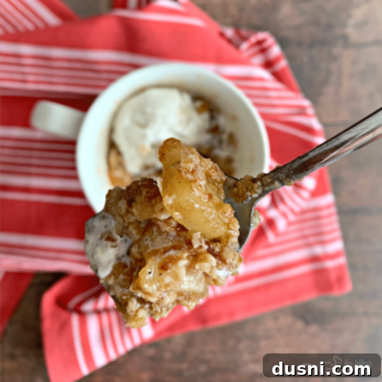 Close-up of a spoonful of Apple Crisp in a Mug, ready to be eaten