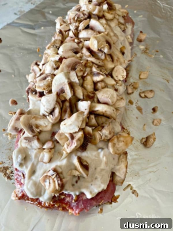 Spreading cream of mushroom soup and adding fresh mushrooms to pork roast