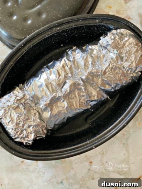Pork roast wrapped tightly in foil, ready for baking