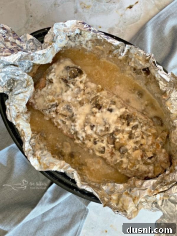 Baked pork roast unwrapped from foil, showing tender meat and gravy