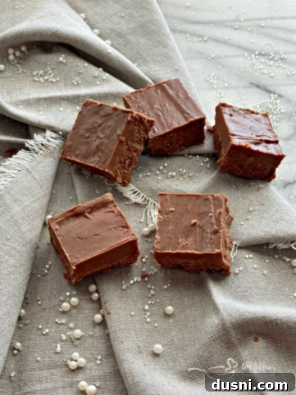 Decorated Never Fail Fudge squares with edible pearls and sparkles for a festive touch.