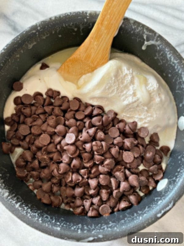 Hot fudge mixture in a pan with chocolate chips and marshmallow creme being stirred in.