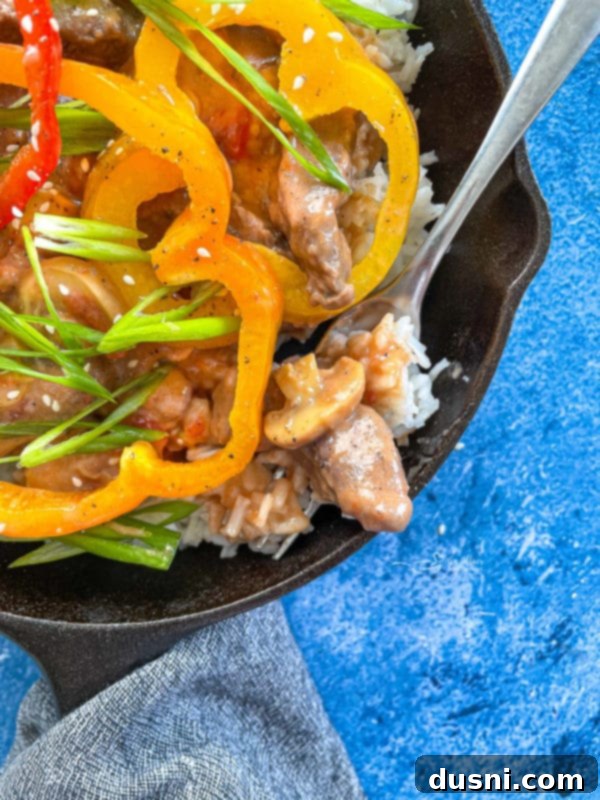 Close-up view of the tender pepper steak with bell peppers and gravy in a cast iron pan, ready to be served.