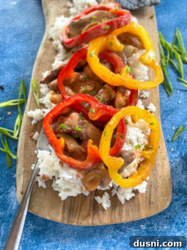 Close-up of a plate with succulent pepper steak, fluffy rice, and bright red, green, and yellow bell peppers, highlighting the vibrant colors and appealing texture.