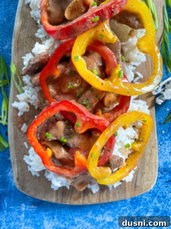 A tantalizing close-up of finished pepper steak, rich with sauce and vibrant bell peppers, served directly from the pan.