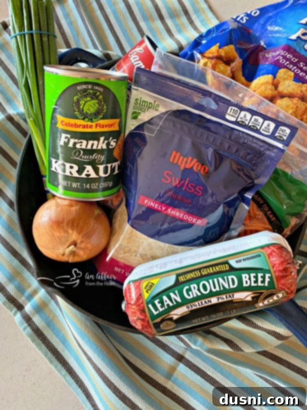 Ingredients for Beef & Kraut Tater Tot Casserole laid out on a table: ground beef, onion, carrots, Frank's Kraut, cream of celery soup, Swiss cheese, tater tots, and scallions.