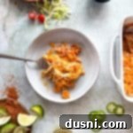 A scoop of Chicken & Doritos casserole and a fork on a white plate.