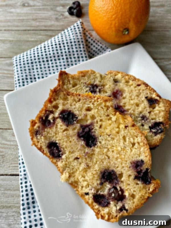 Slices of Blueberry Orange Bread arranged on a white plate, showcasing its tender crumb and blueberry distribution.