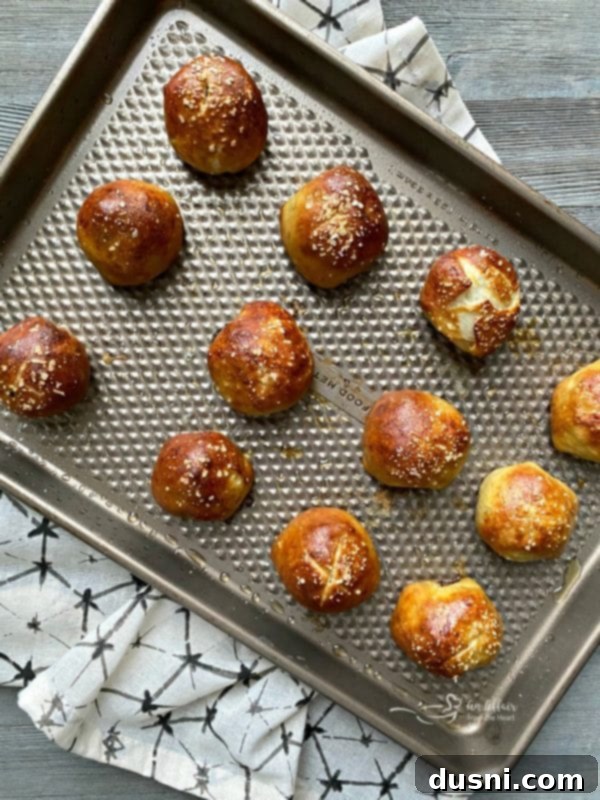 Golden Pretzel Sausage Bites with Zesty Cheese Sauce 15 Freshly baked Sausage Pretzel Bombs cooling on a cookie sheet