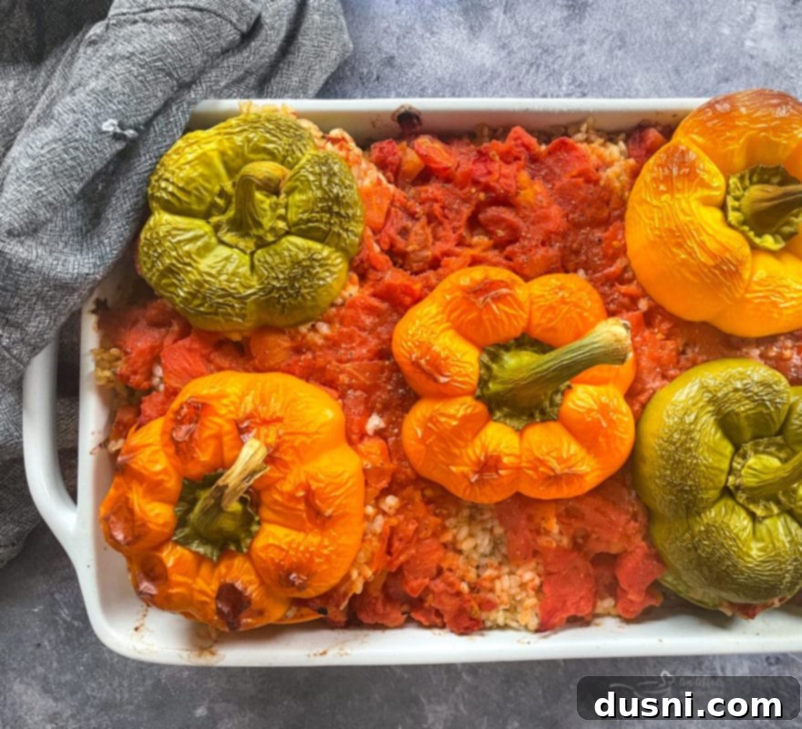 A large baking pan filled with freshly baked, golden-brown stuffed peppers and rice, hot from the oven.