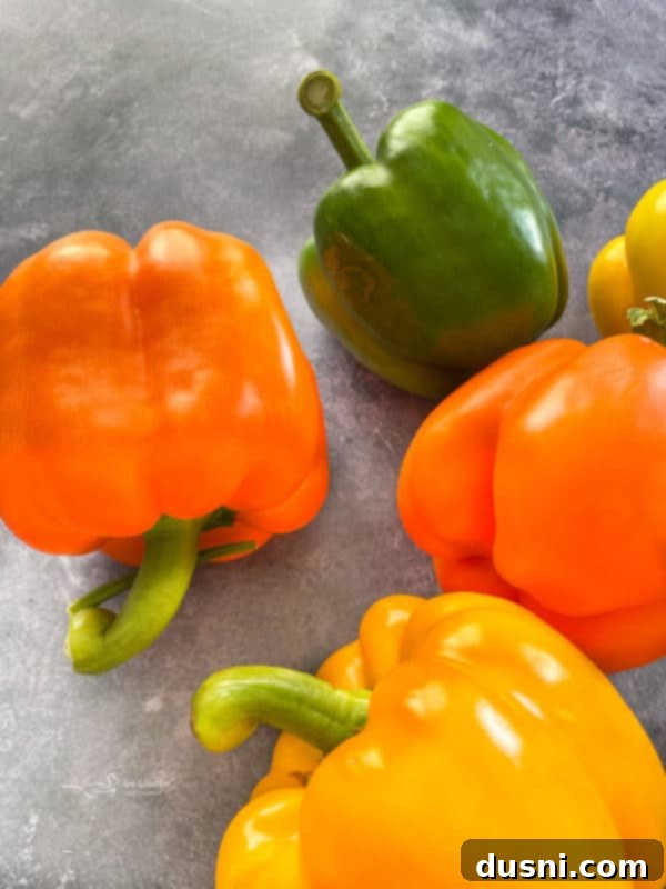 Four vibrant bell peppers in red, yellow, orange, and green colors, ready for stuffing.