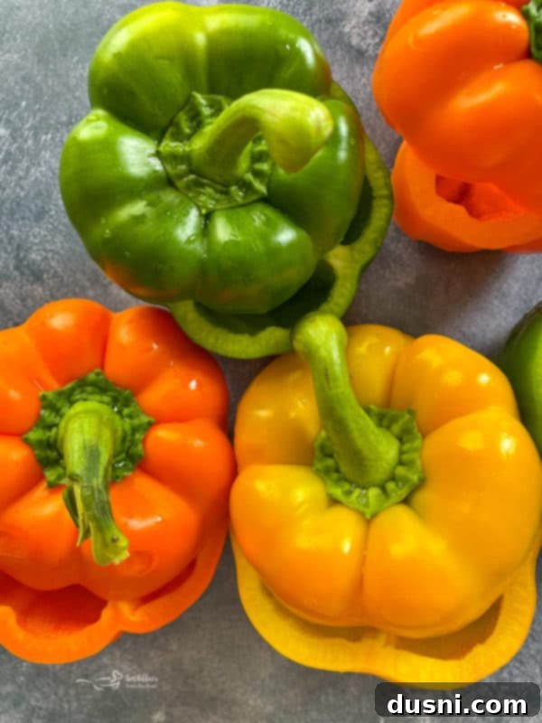 Three perfectly cored and cleaned bell peppers in red, yellow, and green, ready for the stuffing process.