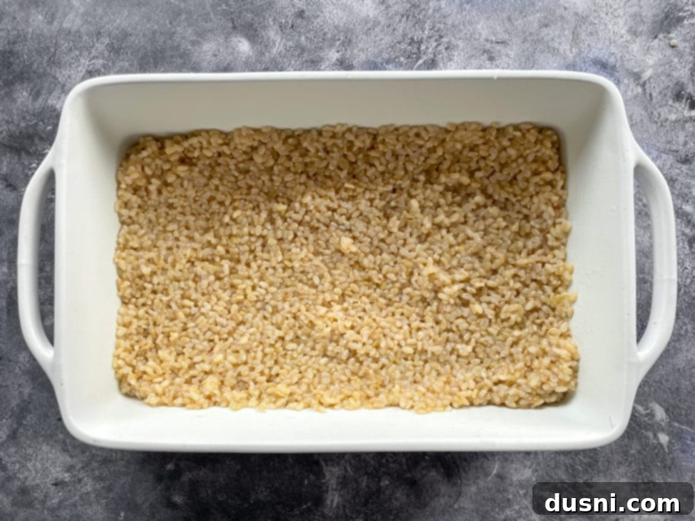 One baking pan partially filled with cooked rice, forming the base for the stuffed peppers.
