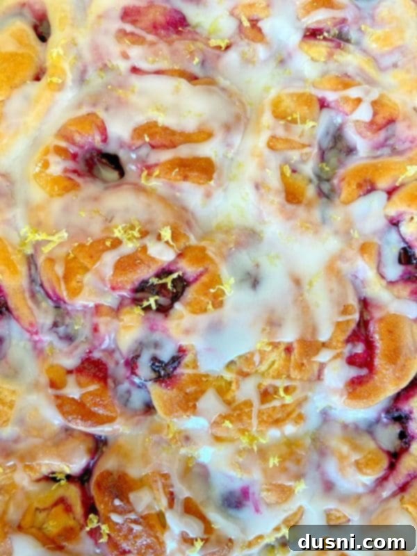 Sunshine Lemon Blueberry Rolls 12 Warm Lemon Blueberry Sweet Rolls with lemon glaze being drizzled