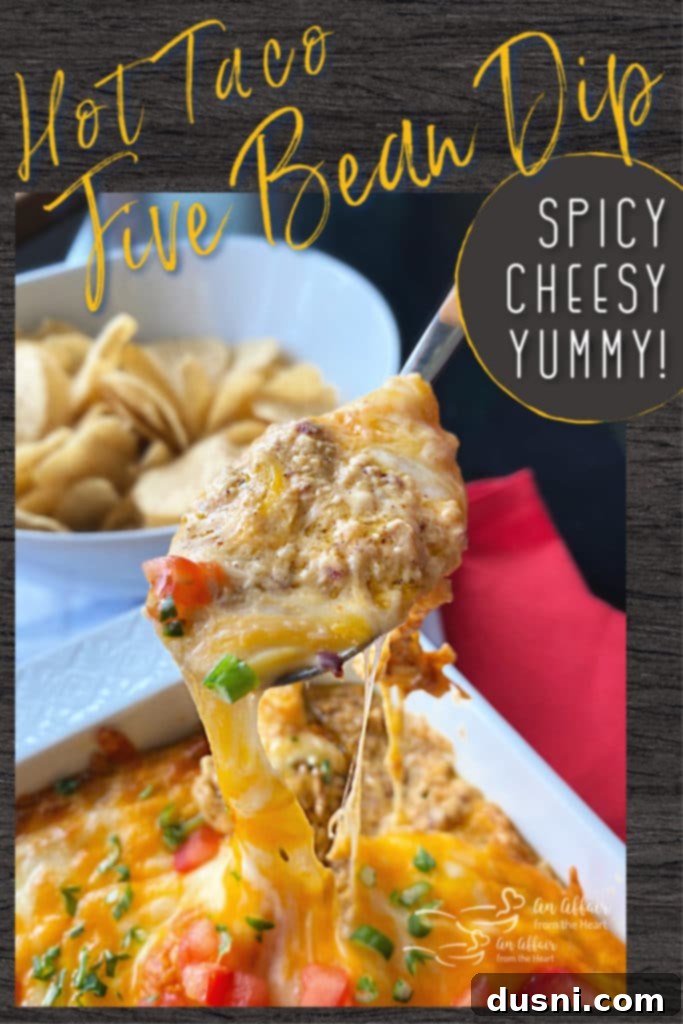 A close-up of Hot Taco Five Bean Dip in a white baking dish, garnished with fresh toppings and ready for serving.