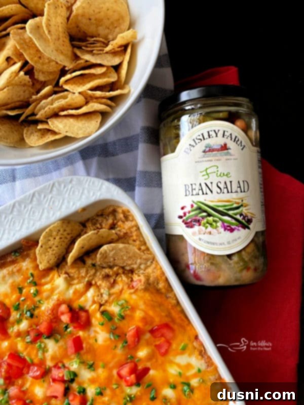 A serving of Hot Taco Five Bean Dip in a bowl with tortilla chips around it.