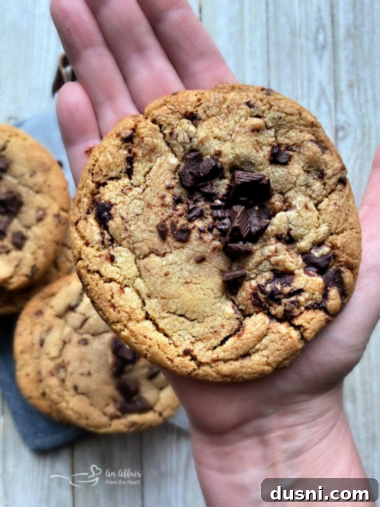 Large, golden-brown Brown Butter Chocolate Chunk Cookies with visible chocolate chunks on a white surface.