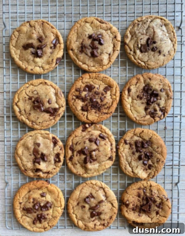 Freshly baked Brown Butter Chocolate Chunk Cookies cooling on a wire rack, with some still on the baking sheet.