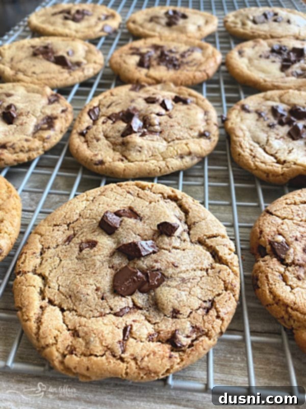 A close-up of a stack of three beautifully baked Brown Butter Chocolate Chunk Cookies, highlighting their rich color and melted chocolate.