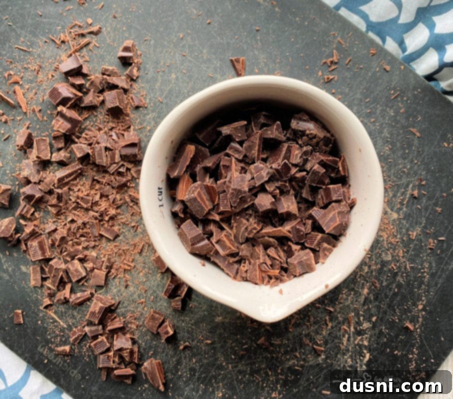Finely chopped bittersweet and semi-sweet chocolate chunks laid out on a cutting board, ready to be added to cookie dough.