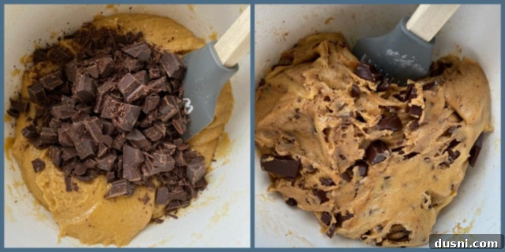 Hands folding dark chocolate chunks into a bowl of brown butter cookie dough.