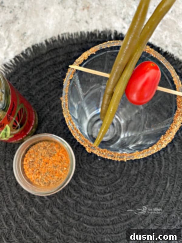 A skewer with pickled green beans and a cherry tomato, prepared as a garnish for the Kicked Up Red Beer.