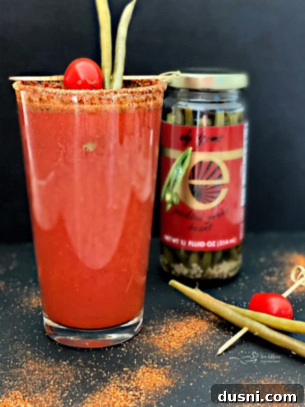 A freshly poured Kicked Up Red Beer with a foamy head, garnished with Ely Farms pickled green beans, ready for enjoyment.