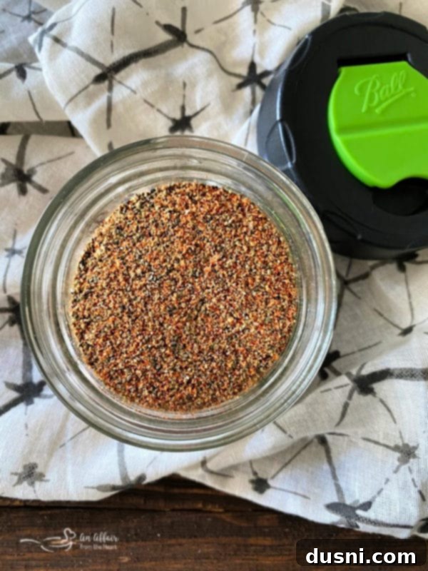 A small jar filled with homemade Bloody Mary Dry Spice blend, showcasing the vibrant colors of the various spices.