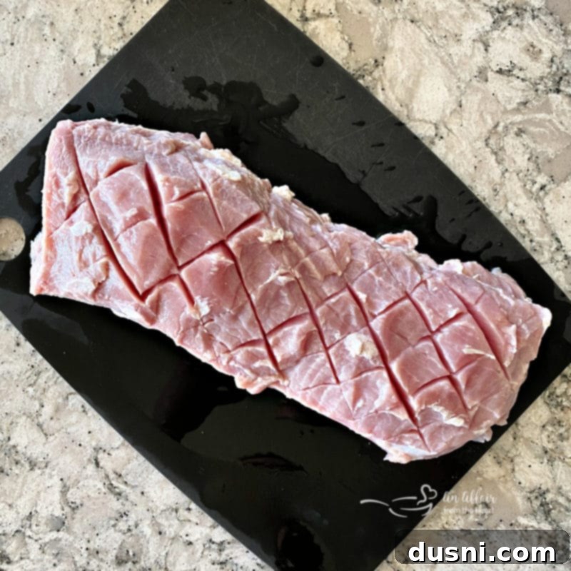 raw pork loin on a cutting board, scored