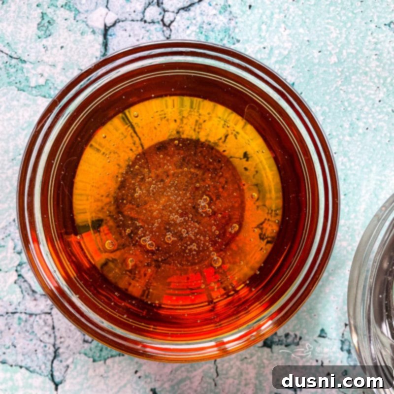 Mixture of water, sugar, and corn syrup simmering in a saucepan for peanut brittle preparation