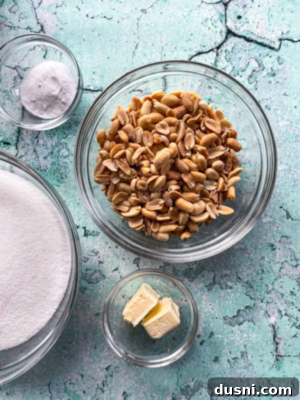 Assortment of key ingredients for making peanut brittle laid out: sugar, corn syrup, vanilla extract, baking soda, butter, and peanuts