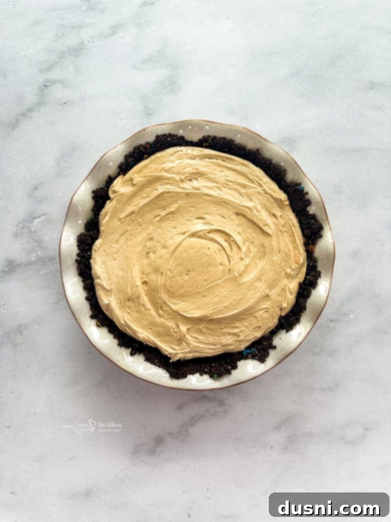 M&M Peanut Butter Bliss Pie 11 The fluffy peanut butter filling being spread into the cooled pie crust.