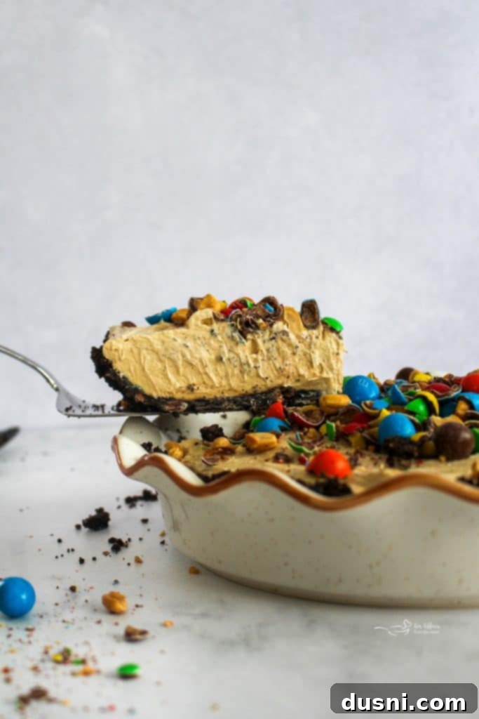 M&M Peanut Butter Bliss Pie 7 A close-up of a slice of Peanut M&M Peanut Butter Pie showing the layered crust and filling.