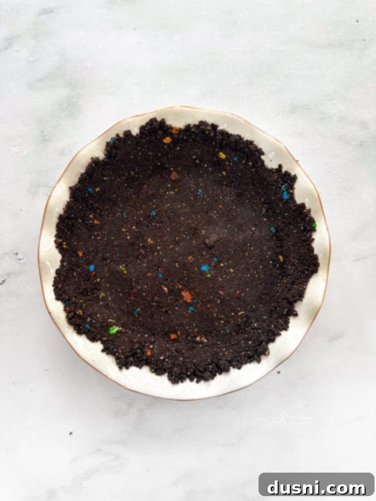 M&M Peanut Butter Bliss Pie 9 Melted butter being poured into the colorful crushed Oreo and M&M crumbs.