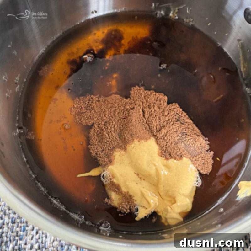 Ingredients for a honey apple glaze being combined in a saucepan on the stovetop