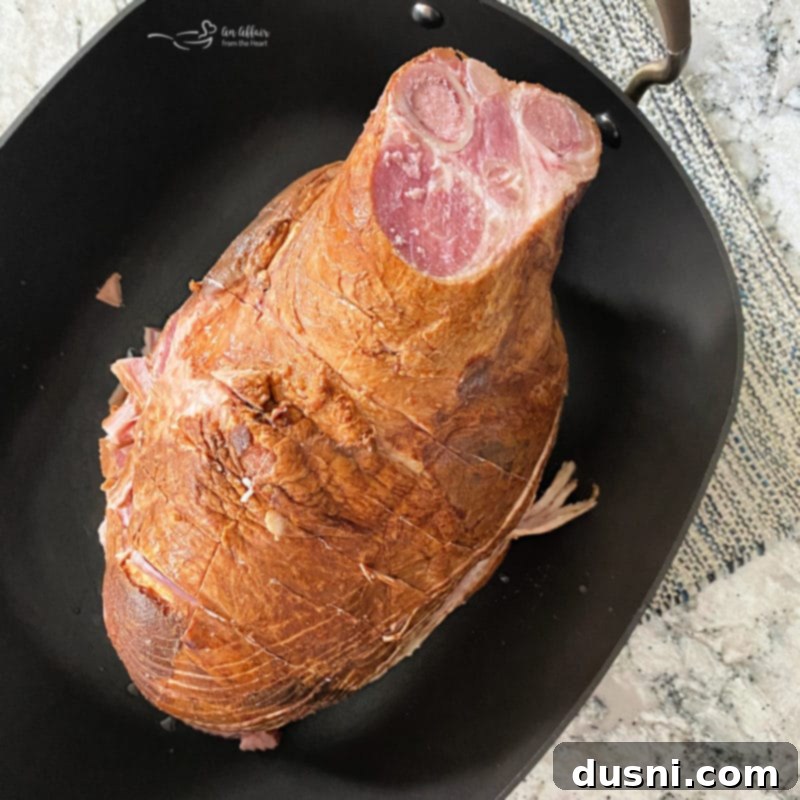 Scoring a bone-in ham with a sharp knife in a criss-cross pattern before placing it on the Traeger grill