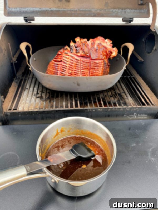 Brushing honey apple glaze onto a smoked ham on a Traeger grill for the second application