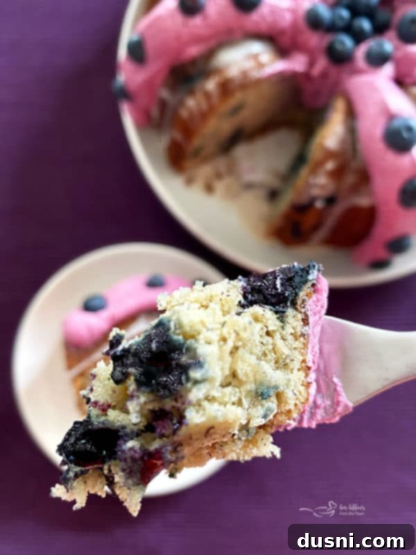 A slice of Blueberry Banana Bundt Cake on a white plate with a fork.