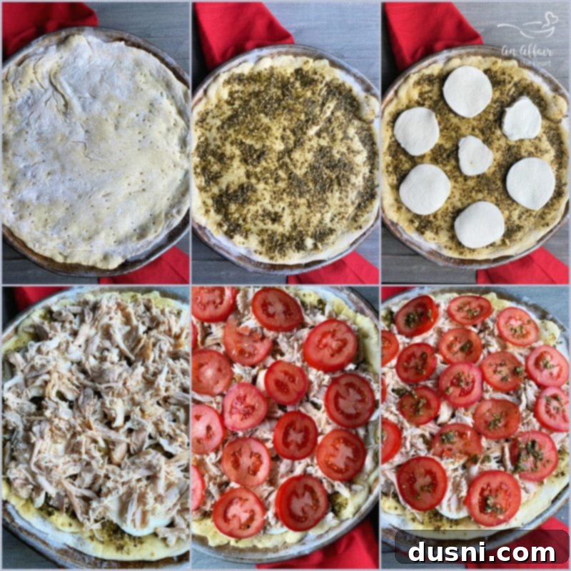 Hands preparing a chicken pesto pizza, adding sliced tomatoes.