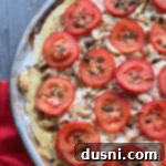 Chicken Pesto pizza up close, showcasing melted cheese and tomatoes.