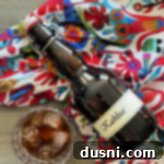 A bottle of homemade Kahlua next to a glass filled with coffee liqueur