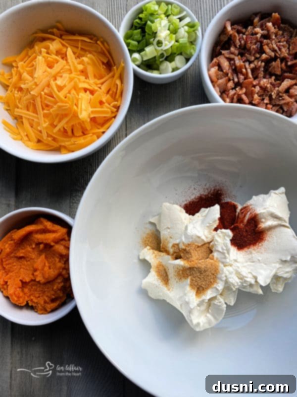 Savory Pumpkin Cheese Dip with Bacon served in a bowl, with a spoon and various dippers like crackers and fresh vegetables.