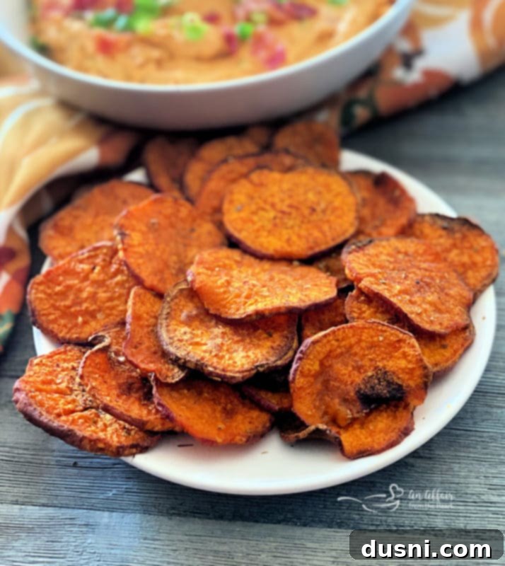 Baked Sweet Potato Chips on a white plate, seasoned with paprika, salt, and oregano, showcasing their golden-orange color and crispy texture.